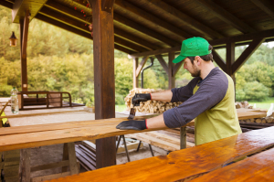 Handyman varnishing wooden planks outside